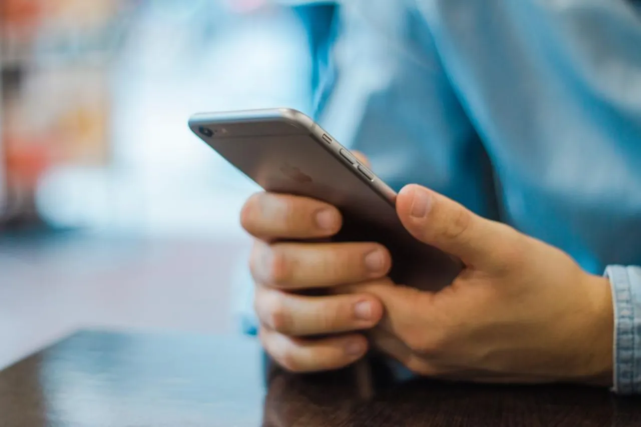 Hand som håller en smartphone vid ett bord