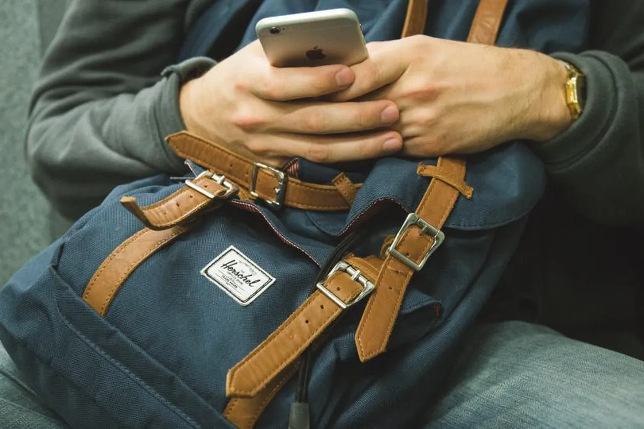 Person som använder mobilen med väskan i knät